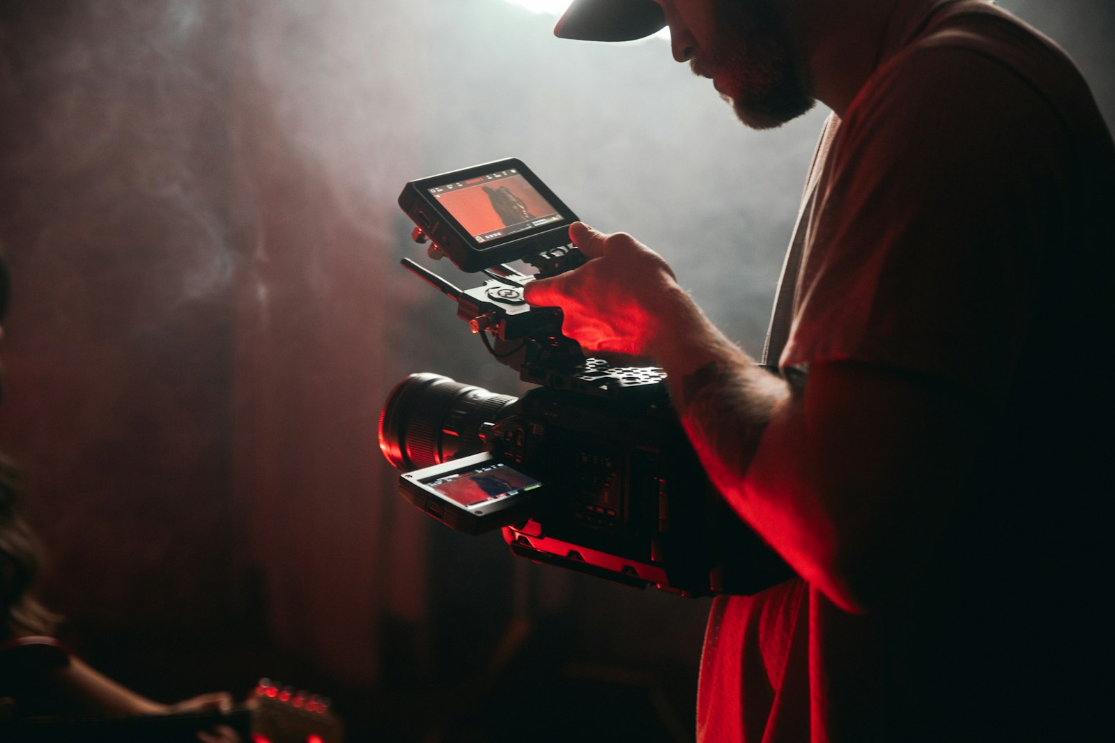 A creator in a white t-shirt holding a black video camera.