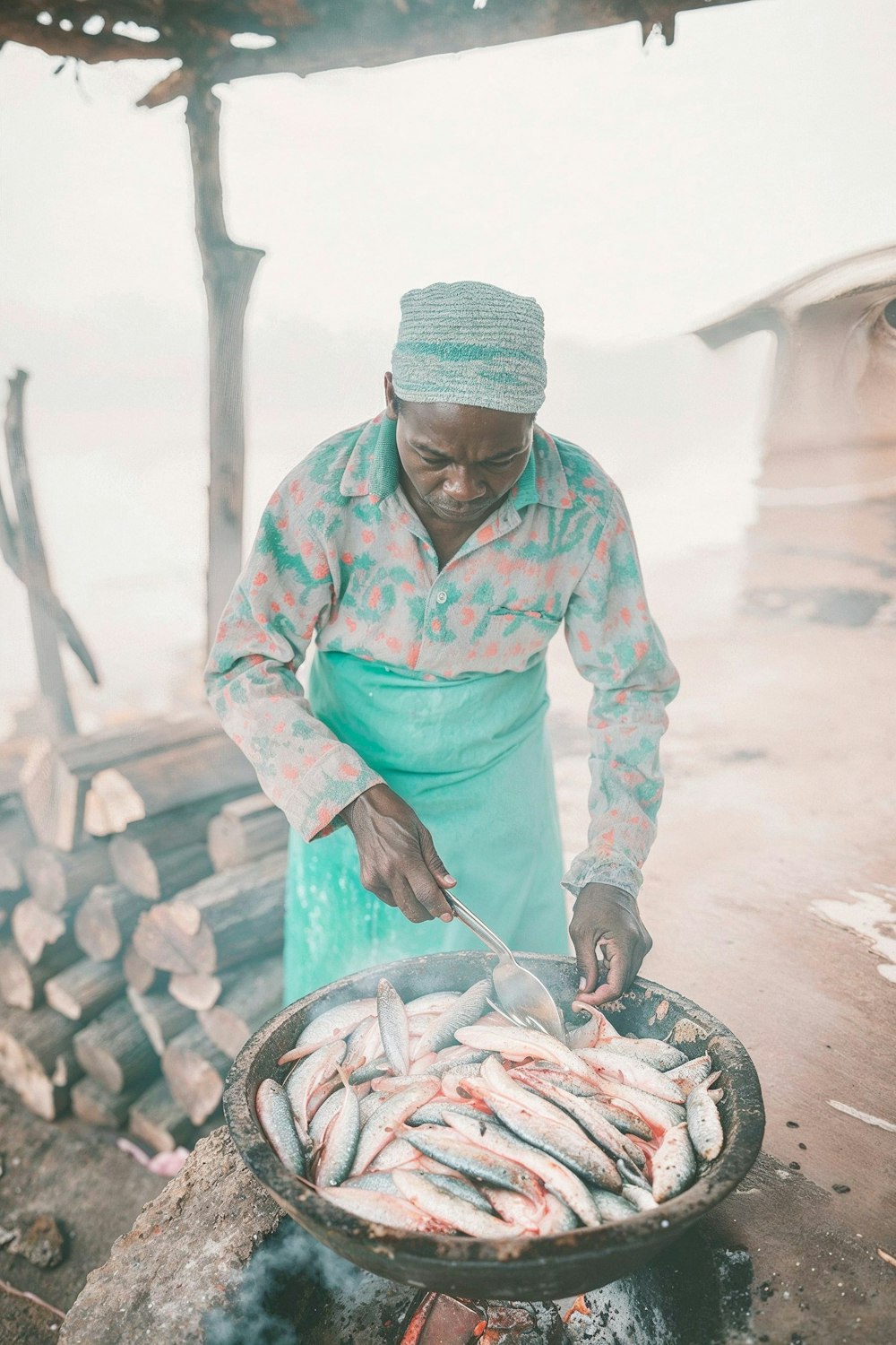 A cook preparing food over an open flame outdoors.